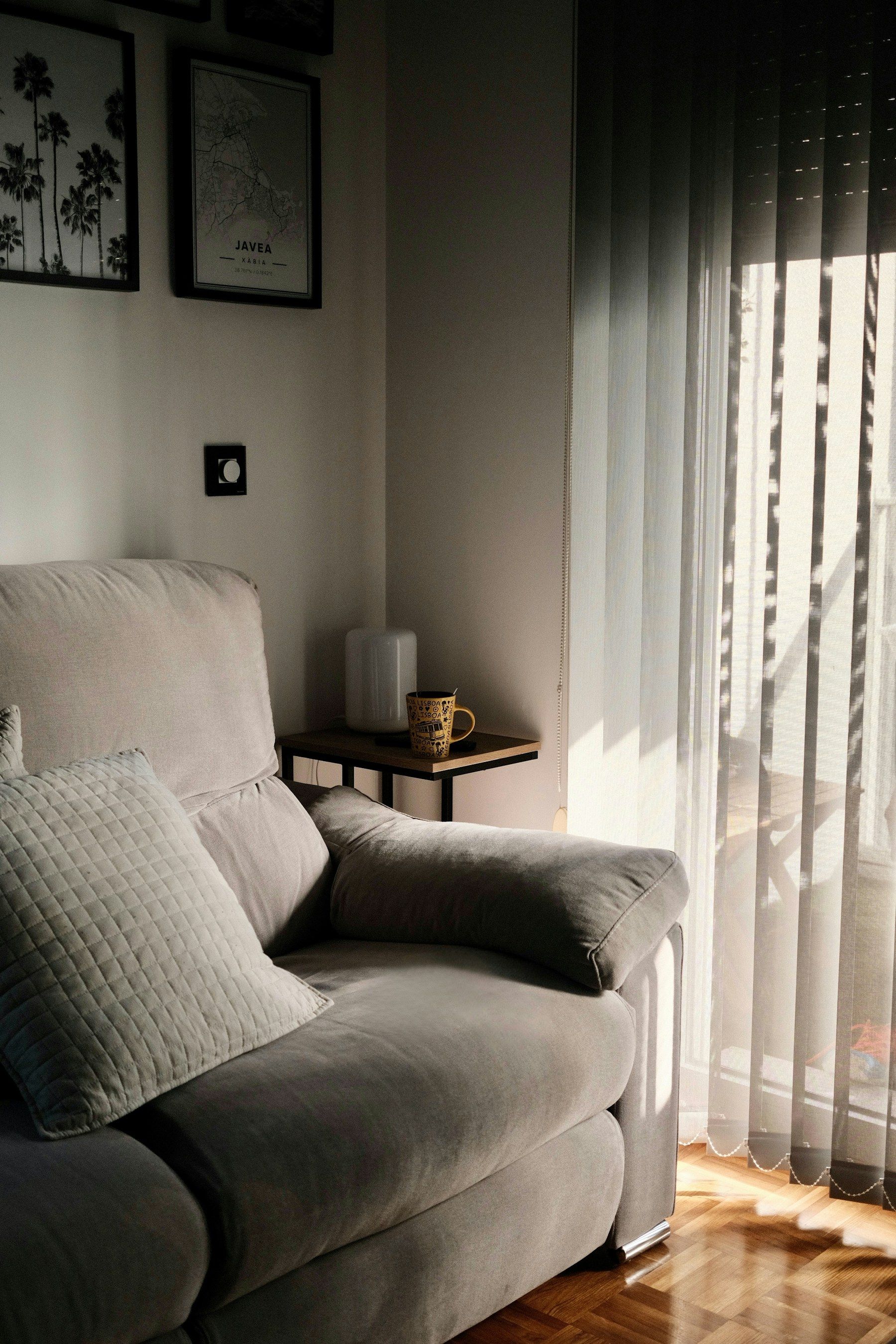 Living room corner in low sunlight, vertical blinds drawn across the window beside an armchair