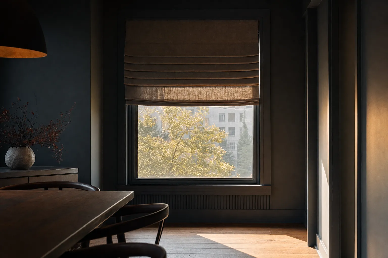 A roman shade raised halfway, its linen folds stacked in soft horizontal pleats above the glass